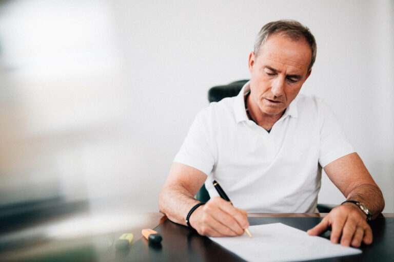 Bodo Schäfer am Schreibtisch mit Stift in der Hand